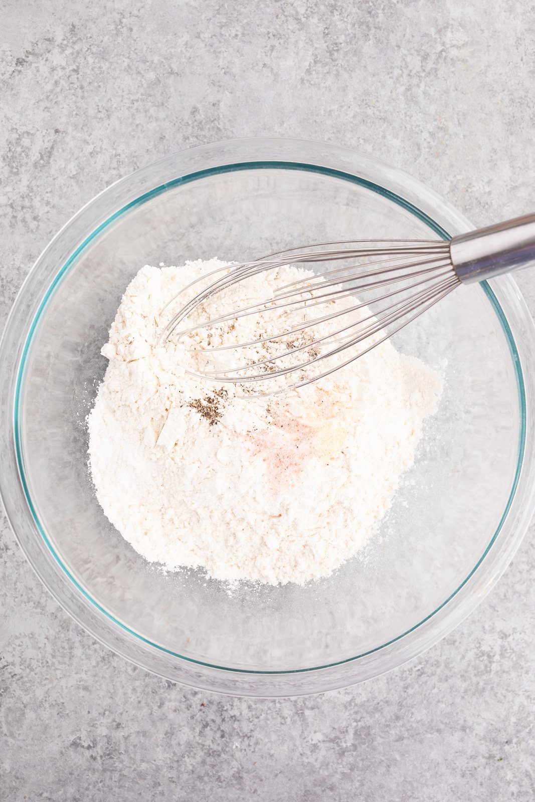 Whisking flour, baking powder, and seasonings in a bowl for savory breakfast biscuits