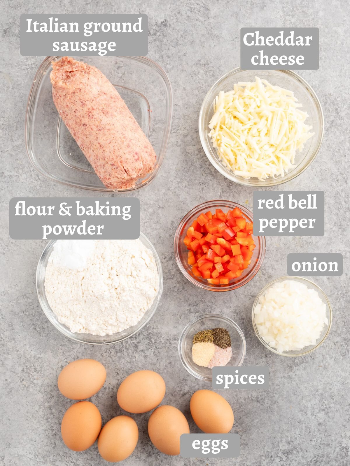 Ingredients for sausage egg breakfast biscuits, including eggs, cheddar cheese, sausage, bell pepper, onion, flour, and seasonings