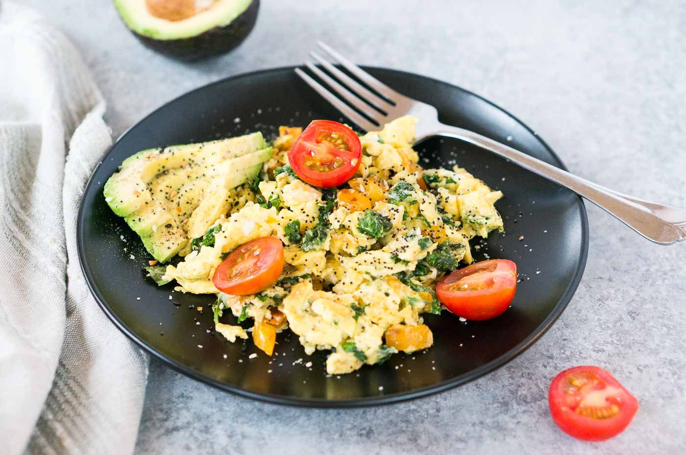 breakfast eggs with tomatoes, peppers and kale on a plate