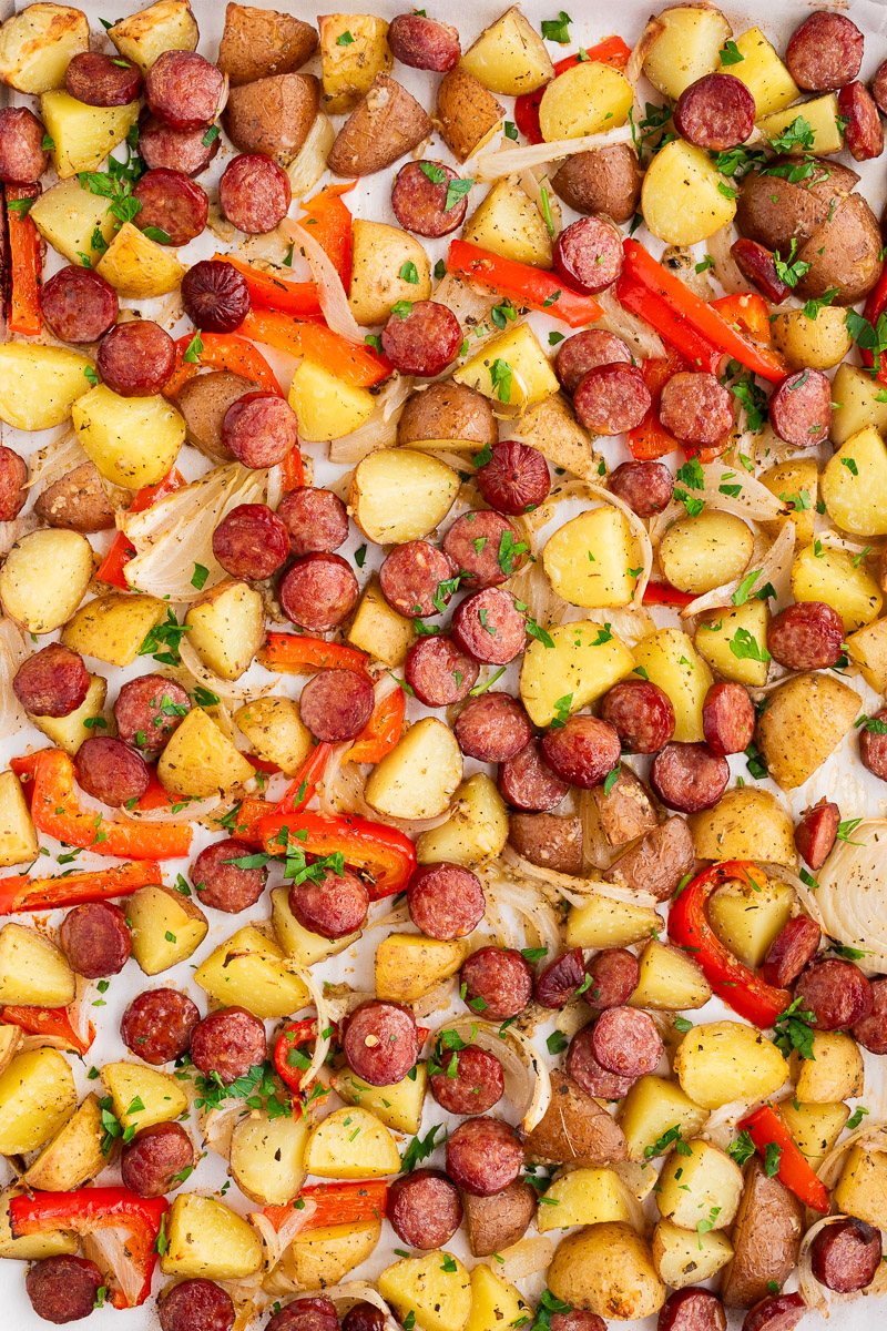 sausage potatoes onions and peppers baked in the oven on a baking sheet