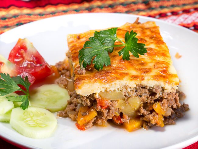 Bulgarian Moussaka on a plate with tomato cucumber salad