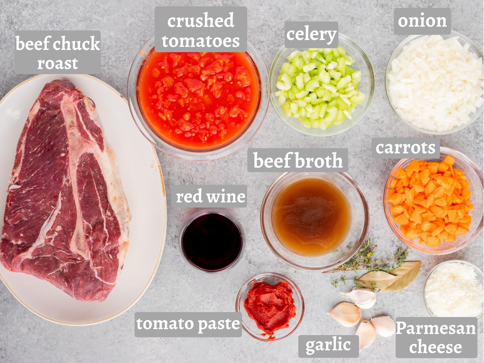 Ingredients for Slow Cooker Beef Ragu including beef chuck roast, crushed tomatoes, onion, celery, carrots, garlic, tomato paste, red wine, beef broth, thyme, bay leaves, and Parmesan cheese.