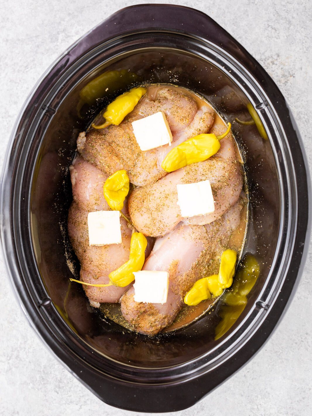 cooking chicken with pepperoncini and seasonings in a slow cooker