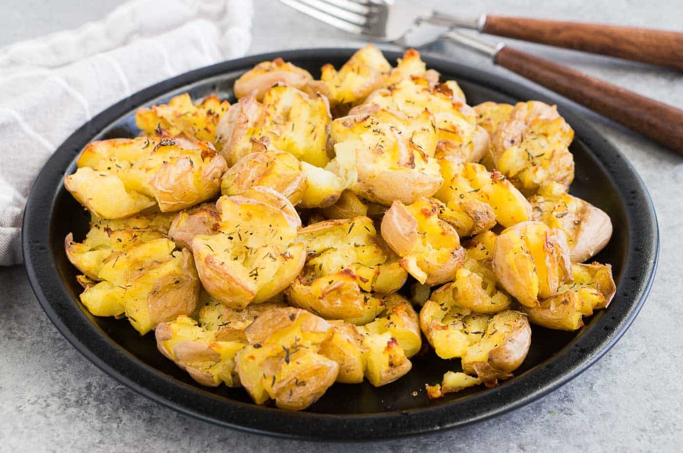 smashed potatoes on a black plate