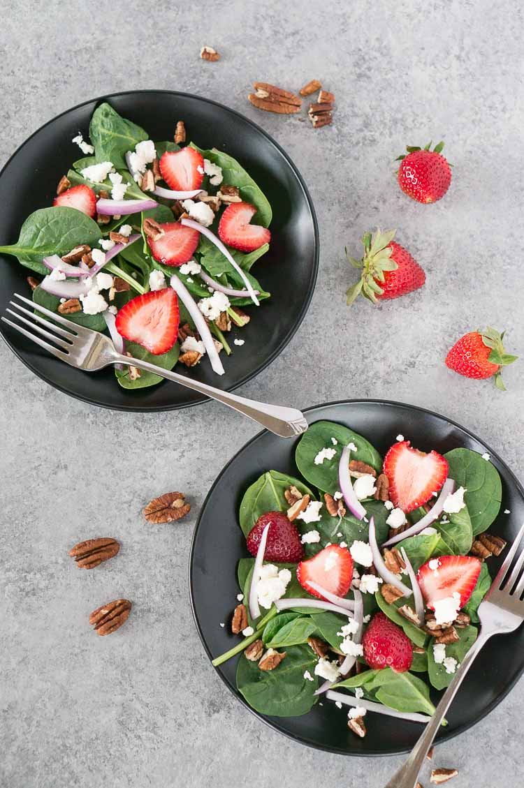 strawberry spinach salad recipe on a black plate with a fork