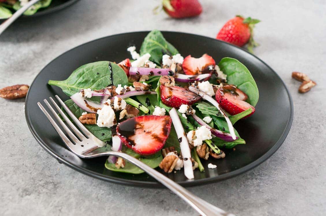 spinach and strawberry salad in a black plate