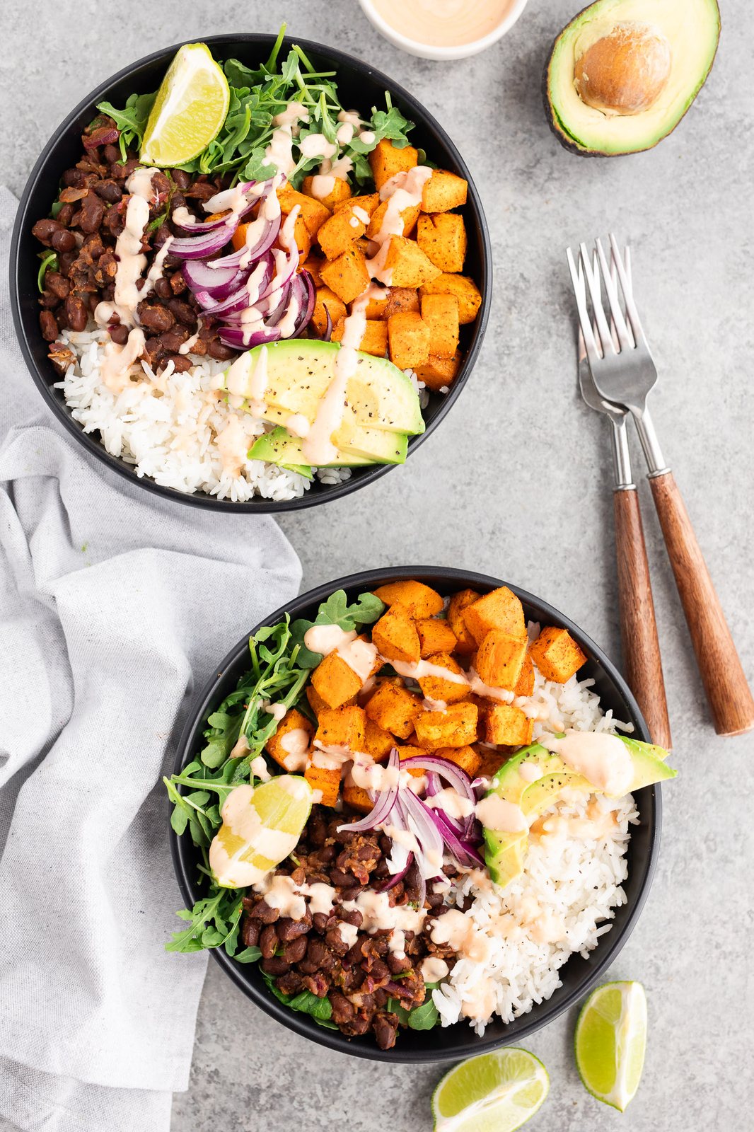 two bowls with rice, arugula, sweet potatoes and black beans