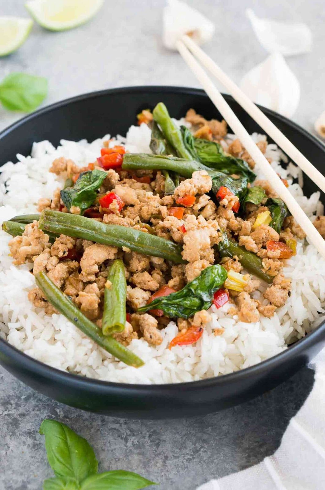 chicken with thai basil over rice in a black bowl