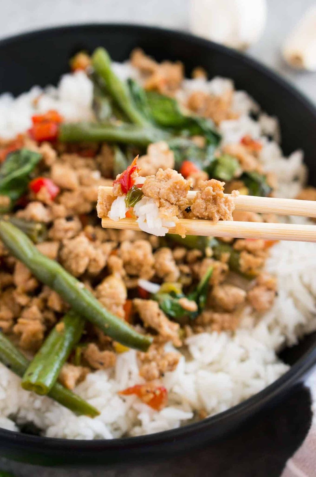 taking a bite of chicken stir fry with chop sticks