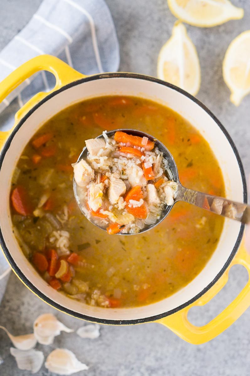 ladle full with soup over a pot with turkey soup