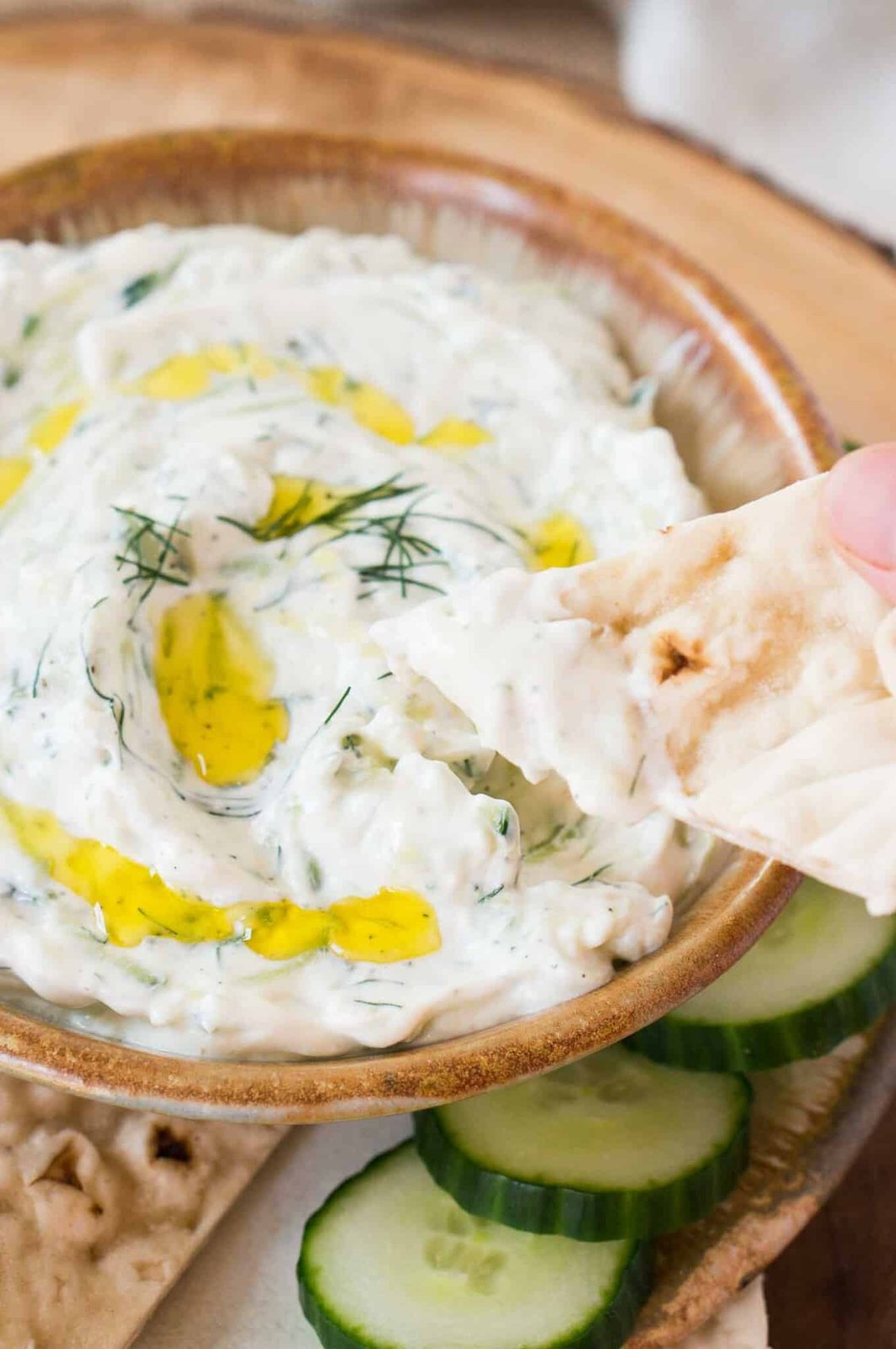 dipping pita bread in tzatziki