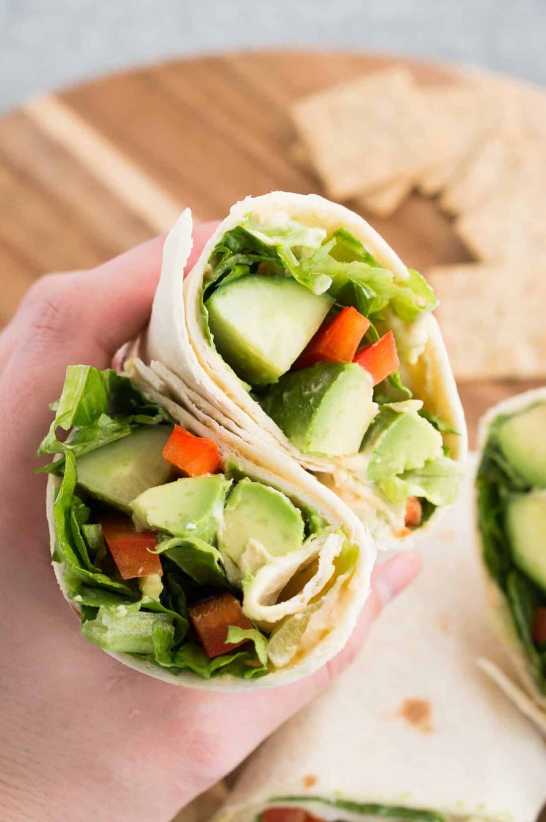 holding a vegan wrap sliced in half