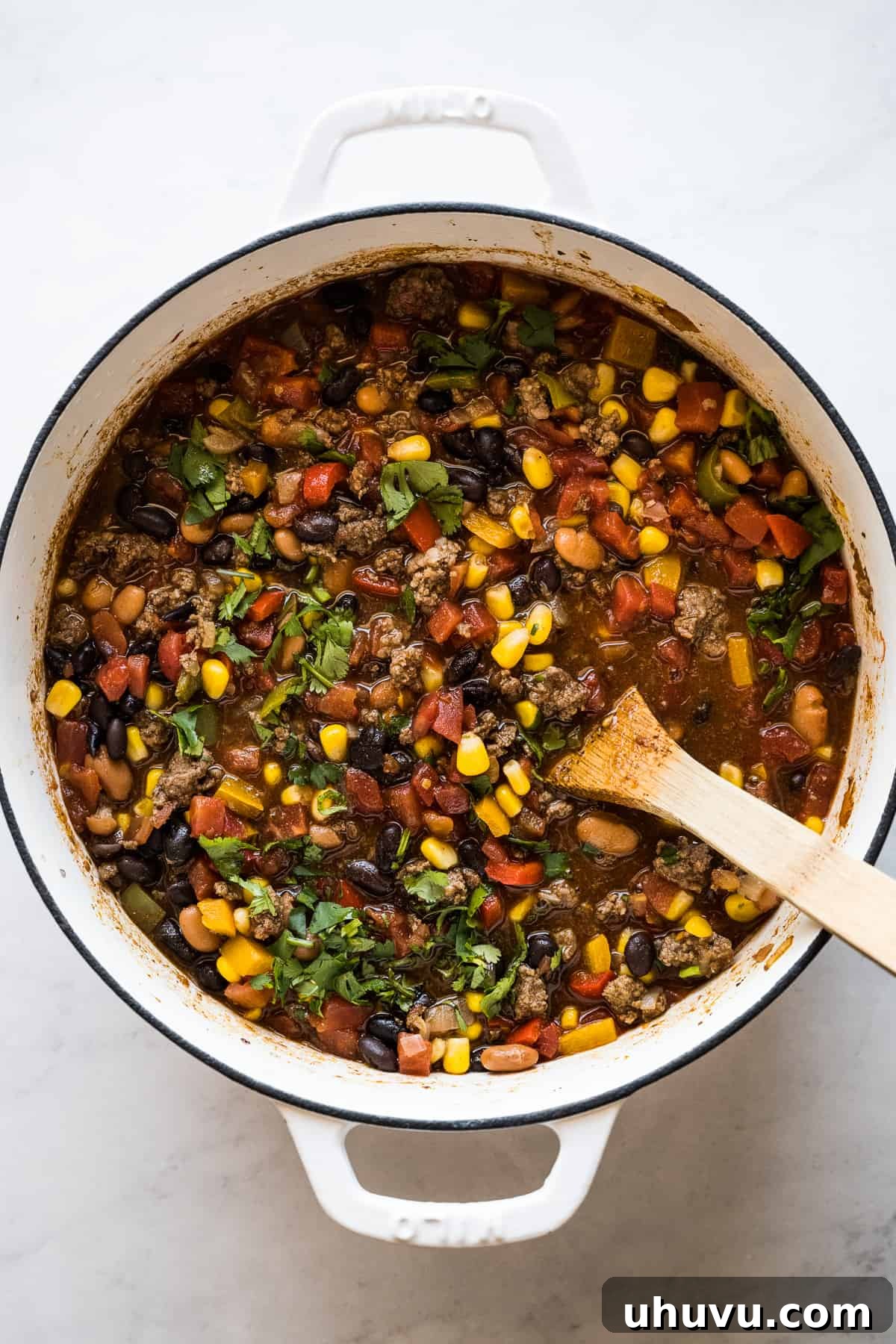 Finished taco soup in a large pot, garnished with fresh cilantro and lime wedges, ready for serving.