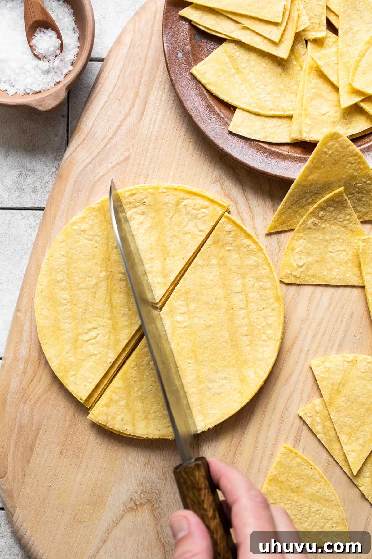 Golden Homemade Tortilla Chips 4 A cutting board with corn tortillas being sliced into perfect triangles, ready to become homemade tortilla chips.