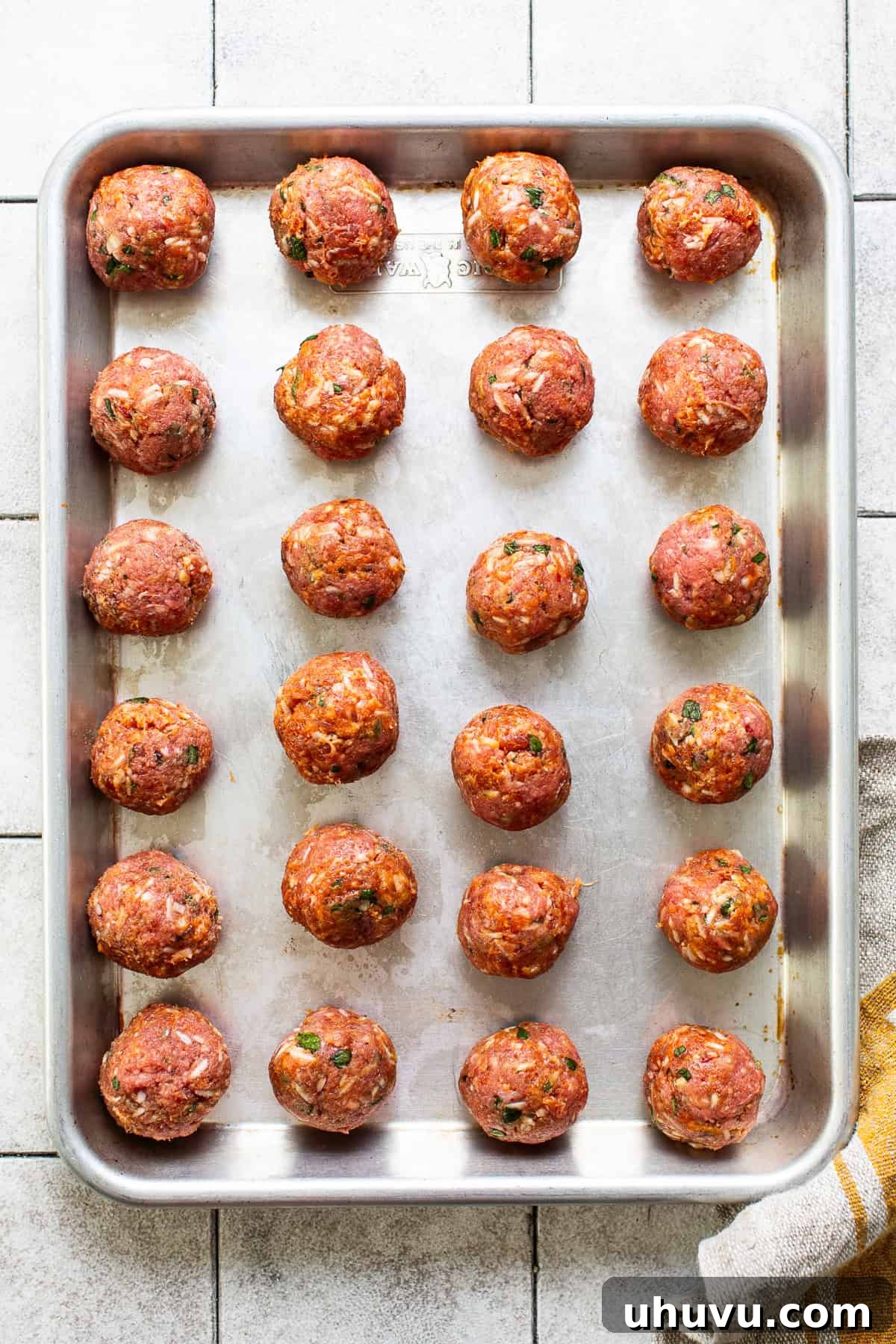 24 formed meatballs on a baking sheet ready to be cooked for Mexican albondigas soup.