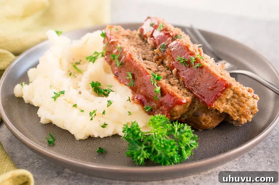 Close-up of baked meatloaf slices on a plate with creamy mashed potatoes, showcasing the rich glaze and tender texture.