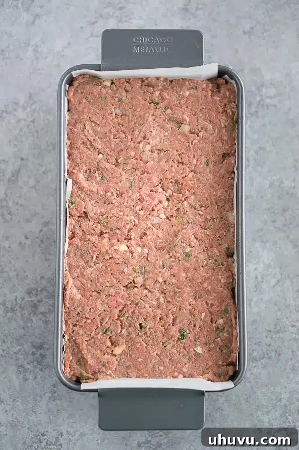 Uncooked meatloaf mixture perfectly shaped in a baking pan, ready for the oven to become a delicious meal.
