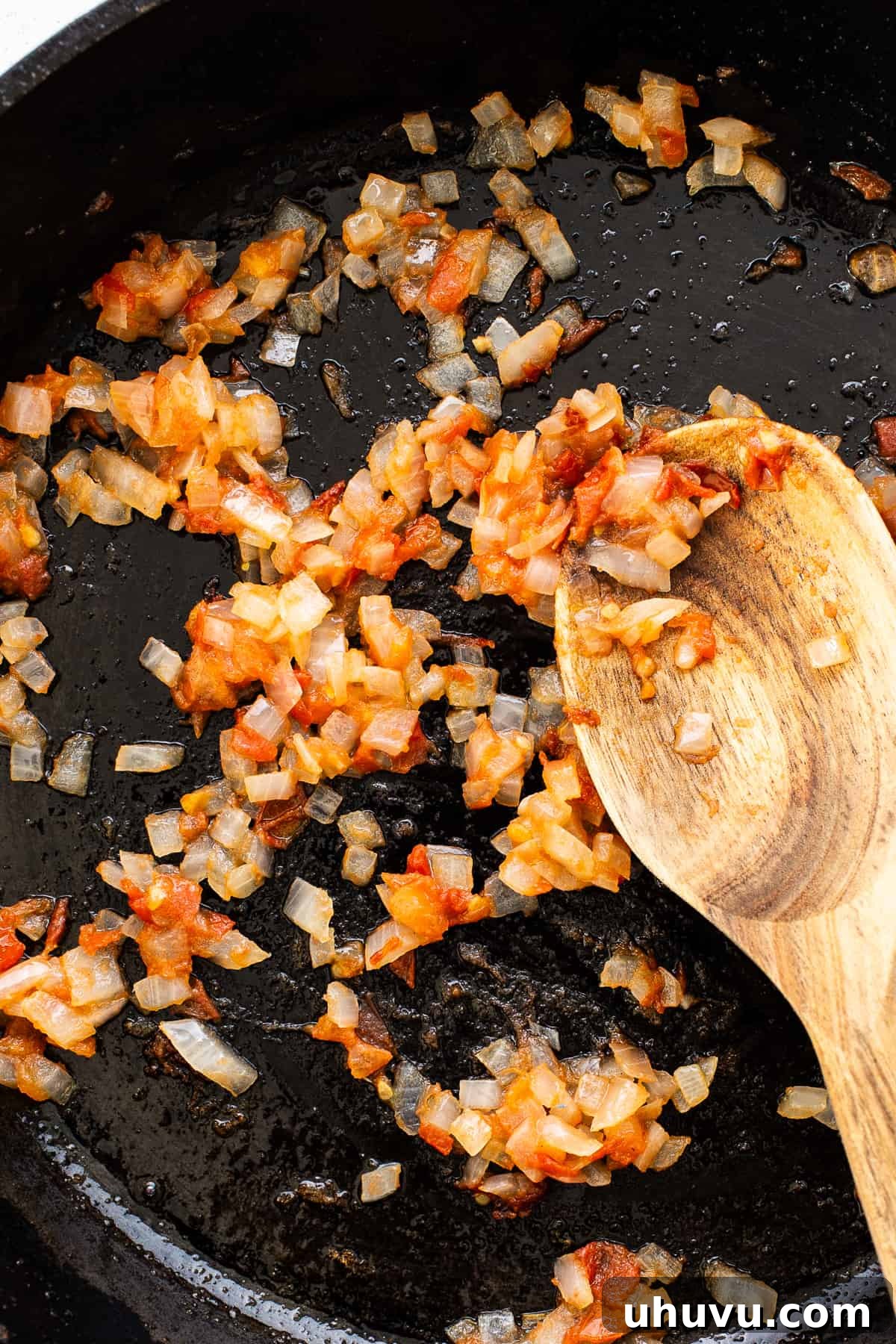 Fiery Chorizo Morning 4 A medium skillet on a stovetop containing finely chopped onions, tomatoes, and minced garlic, gently sautéing to create a fragrant base for the chorizo and eggs.