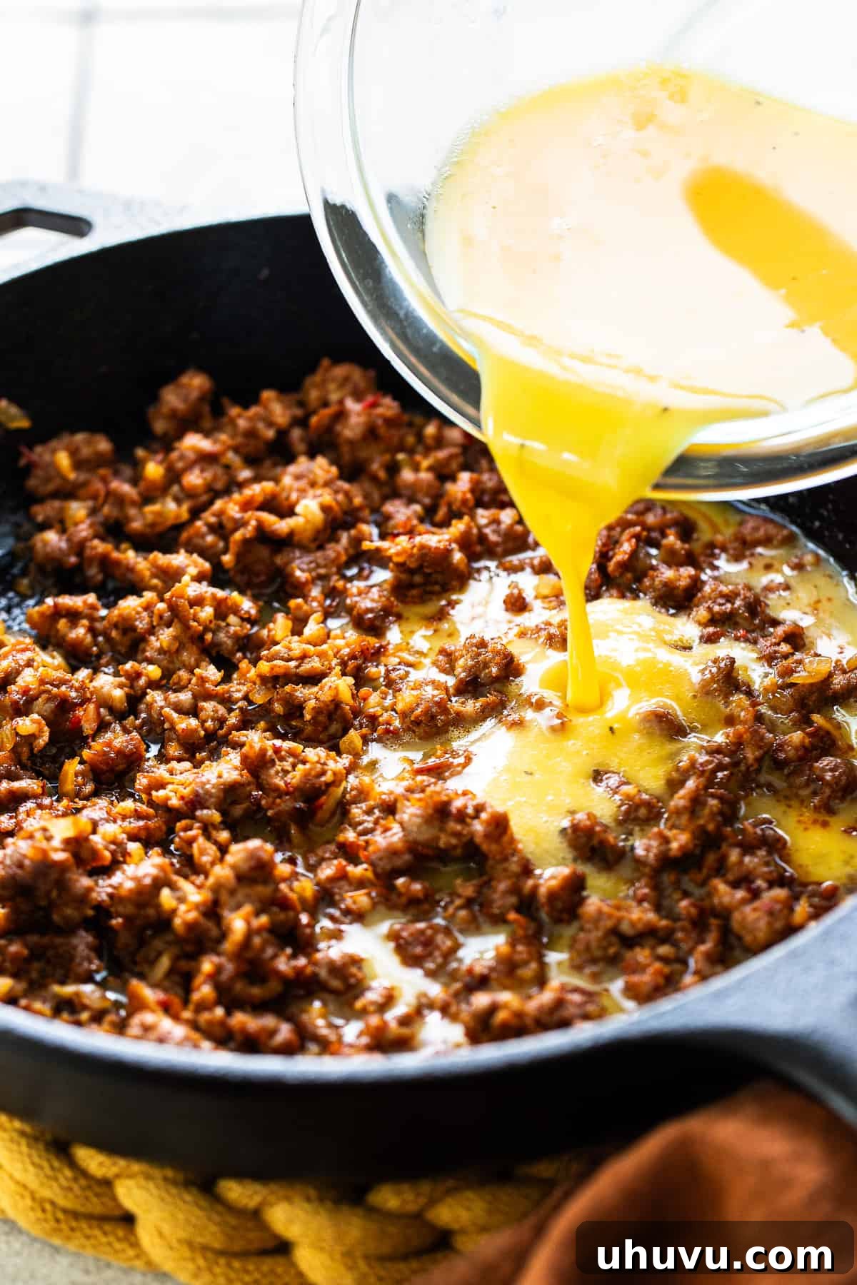 Fiery Chorizo Morning 6 Whisked eggs being carefully poured into a hot skillet, mingling with the rich, cooked Mexican chorizo, beginning the scrambling process.