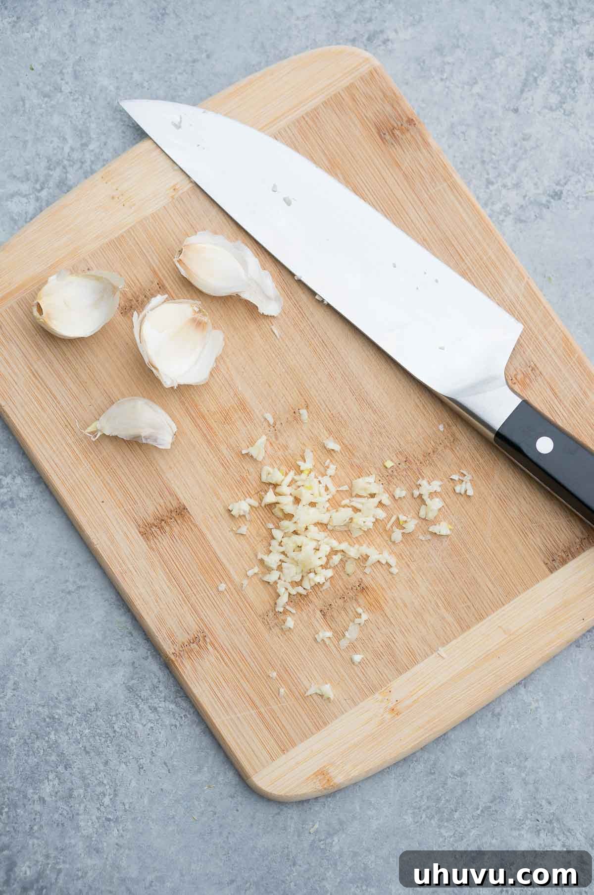 Master the Art of Cutting Garlic 2 Perfectly minced garlic on a wooden cutting board, ready for cooking and infusing dishes with rich flavor
