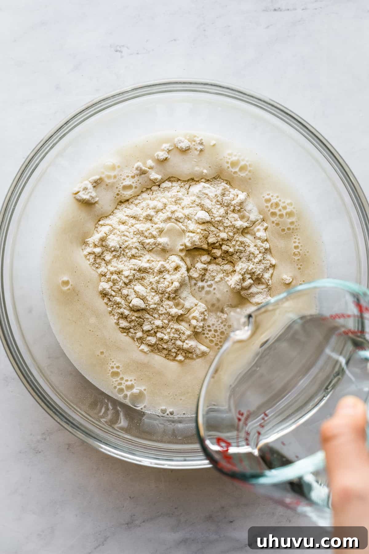 Warm water being carefully poured into the bowl of masa harina to begin forming the dough for corn tortillas.