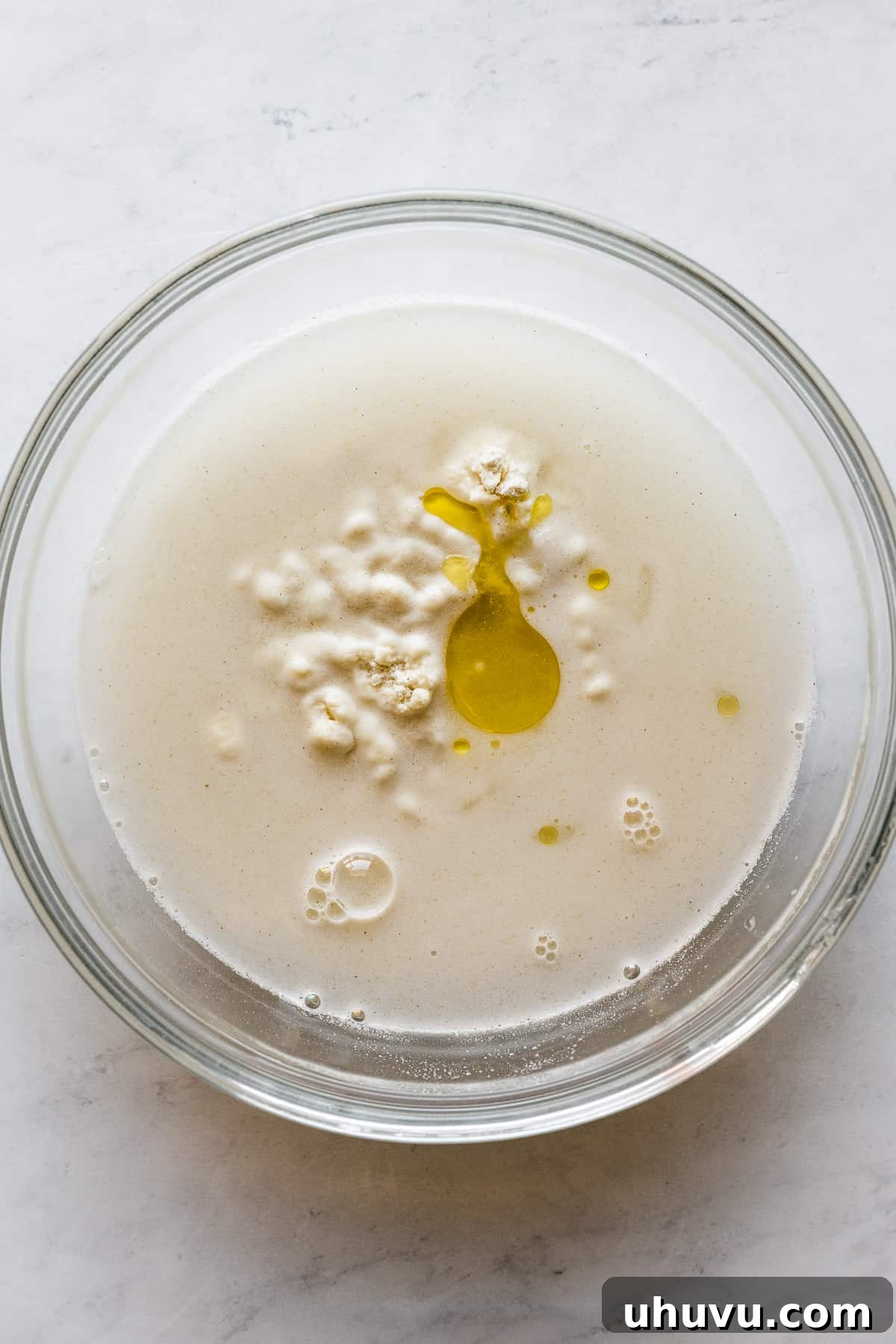 Oil, water, salt, and masa harina in a bowl, coming together to form a dough.