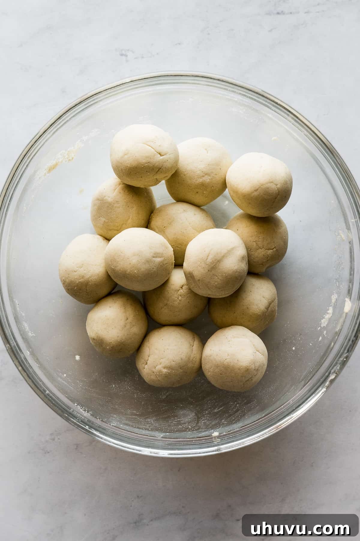 Neatly formed balls of masa harina dough resting in a bowl, covered for freshness.