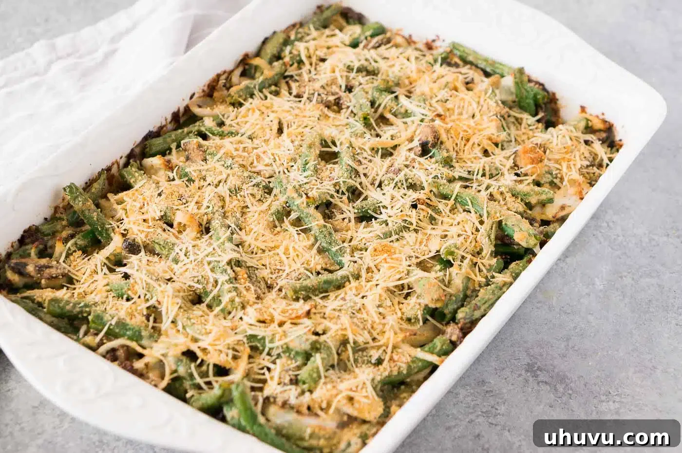 A freshly baked healthier green bean casserole bubbling in a glass baking dish, ready to be served.