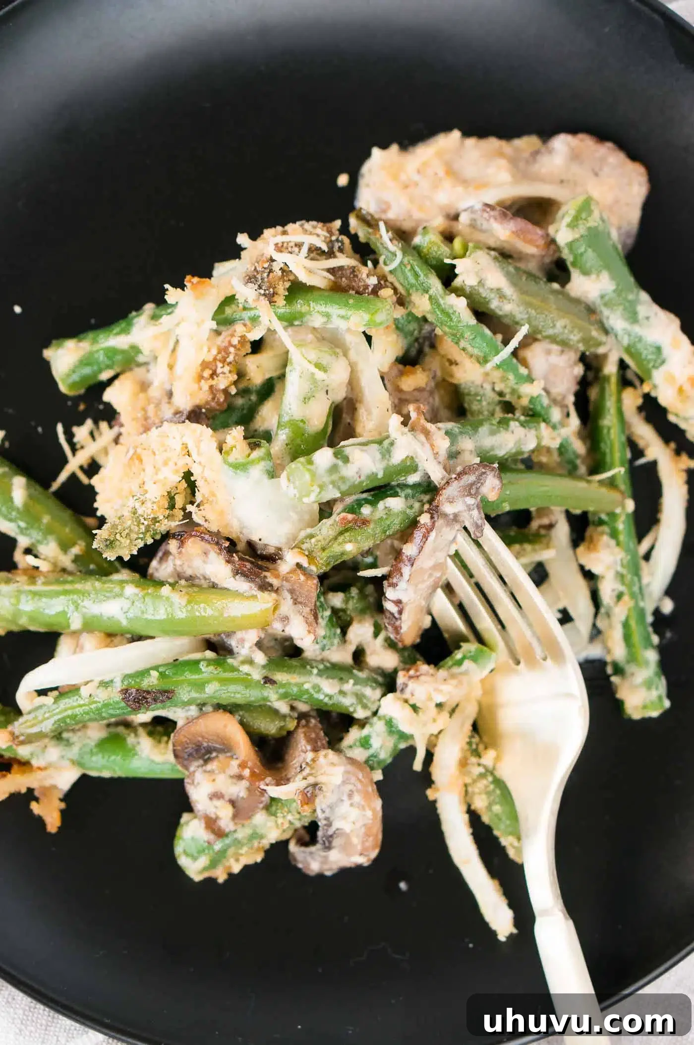 A close-up image of a serving of Thanksgiving green bean casserole on a white plate, ready to be enjoyed.