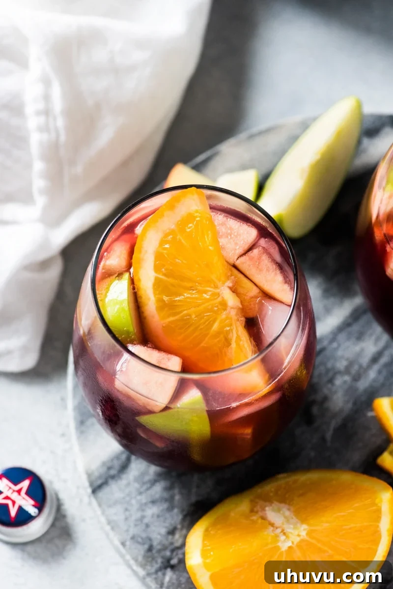 A selection of glasses filled with easy sangria, showcasing the vibrant red wine, fresh apples, and juicy oranges.