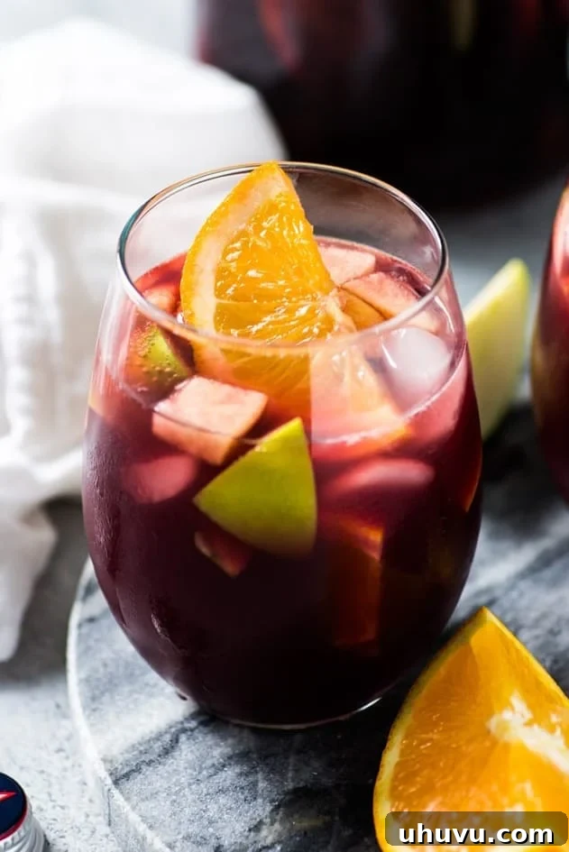 A vibrant pitcher of Classic Red Sangria, featuring red wine and an assortment of fresh fruits like apples and oranges, ready to be served.