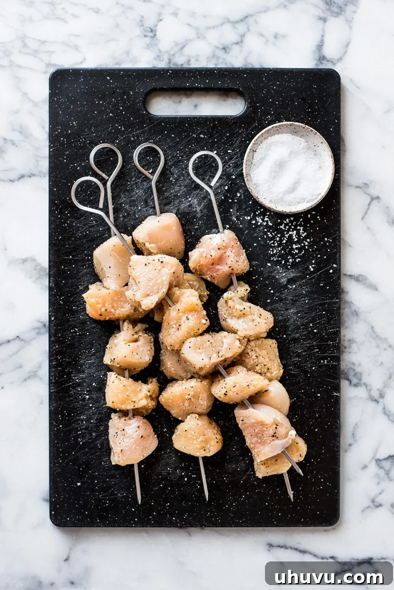 Succulent Chicken Kabobs Recipe 3 Uncooked chicken kabobs seasoned with kosher salt and black pepper, ready for grilling.