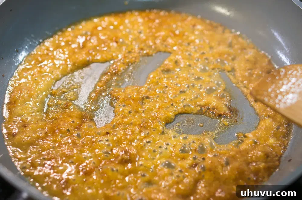 The simmering peach sauce with fresh peach slices and rosemary