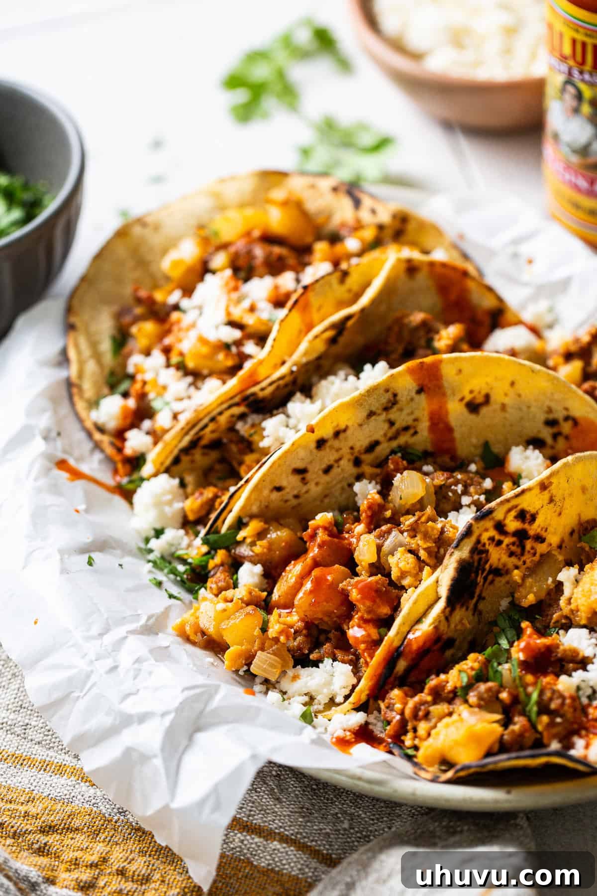 Morning Taco Bliss 2 Breakfast tacos made from potatoes, chorizo, and eggs topped with queso fresco, cilantro, and hot sauce. A vibrant, mouth-watering image showing the delicious ingredients.