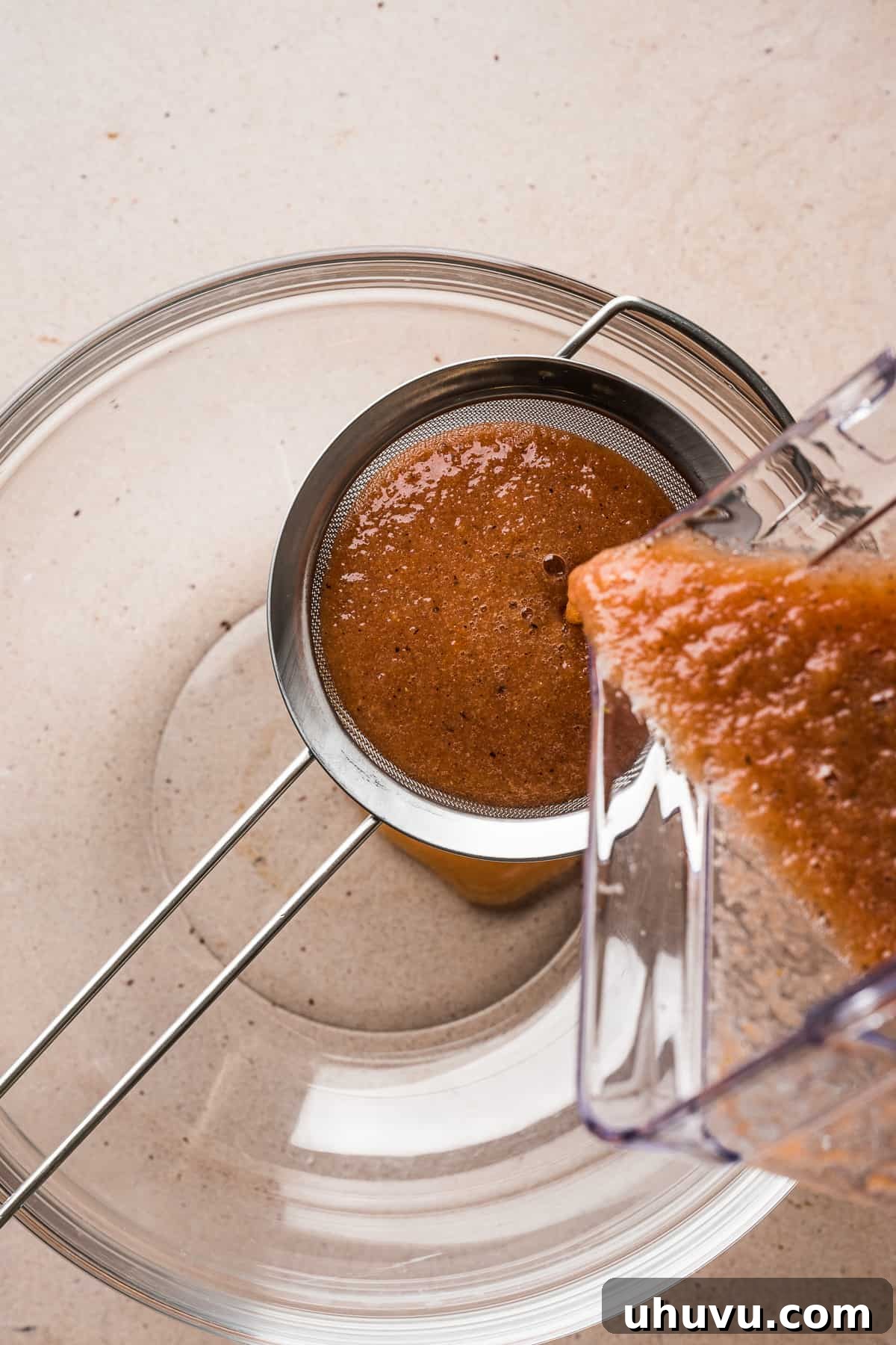 Freshly blended tomato sauce for Sopa de Fideo being carefully strained through a fine-mesh sieve to achieve a smooth consistency.