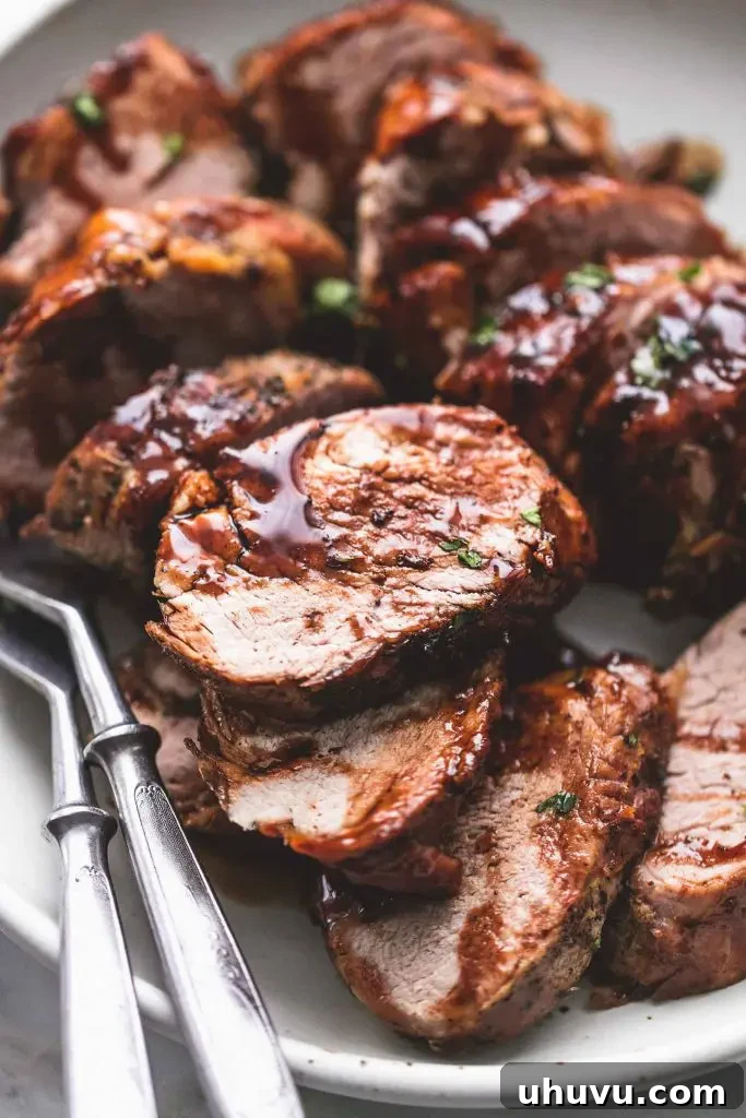 Platter of sliced balsamic glazed pork tenderloin, garnished with herbs