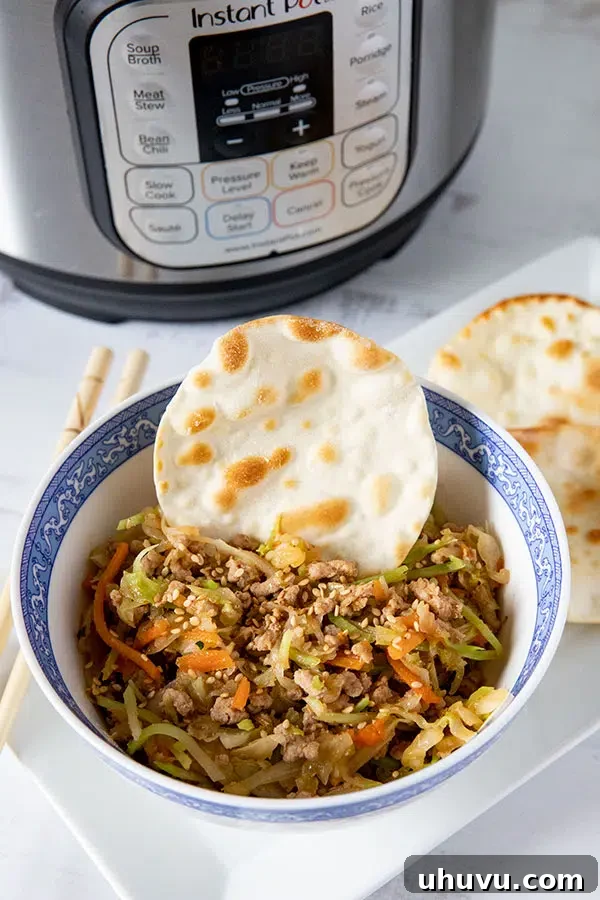 Bowl of savory egg roll filling, commonly known as Egg Roll in a Bowl, next to an Instant Pot