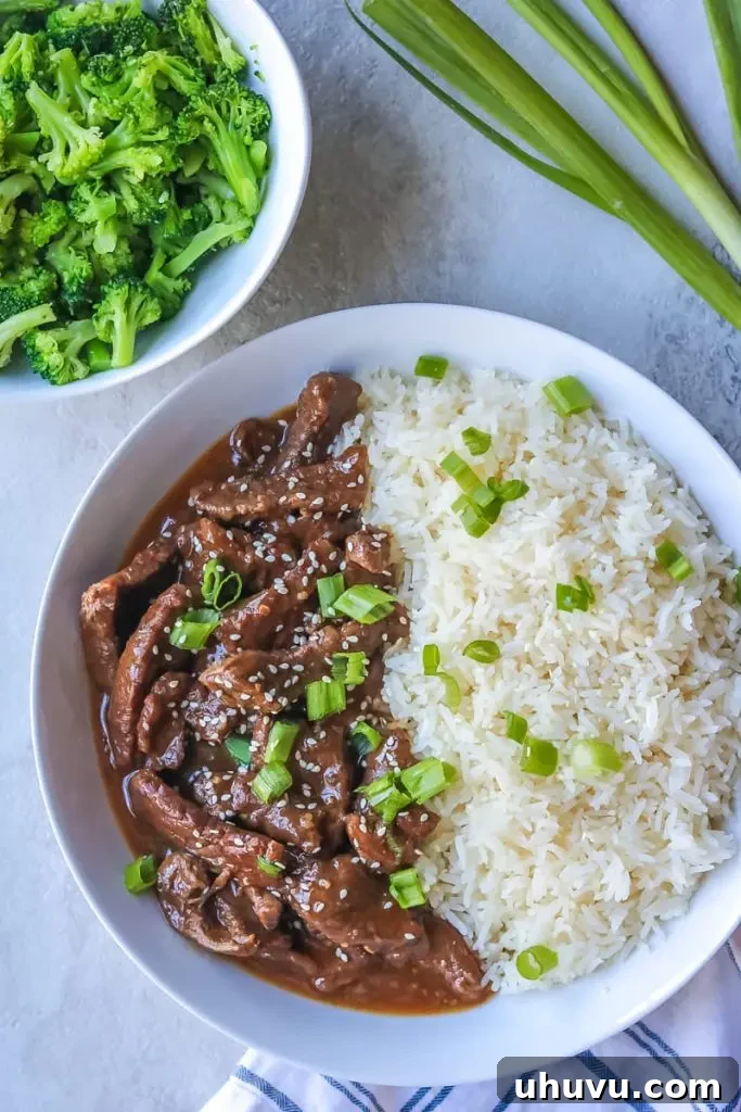 Instant Pot Mongolian Beef served with fluffy white rice, garnished with green onions