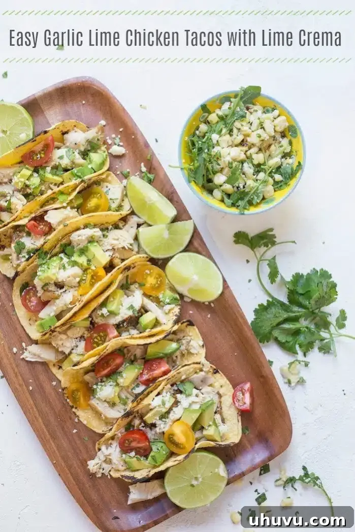 chicken tacos with fresh avocado and tomatoes on a wooden platter