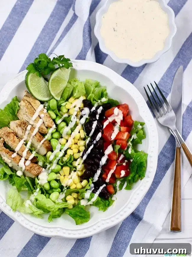 BBQ Chicken Salad with dressing on a plate with fork and knife, a vibrant and healthy meal