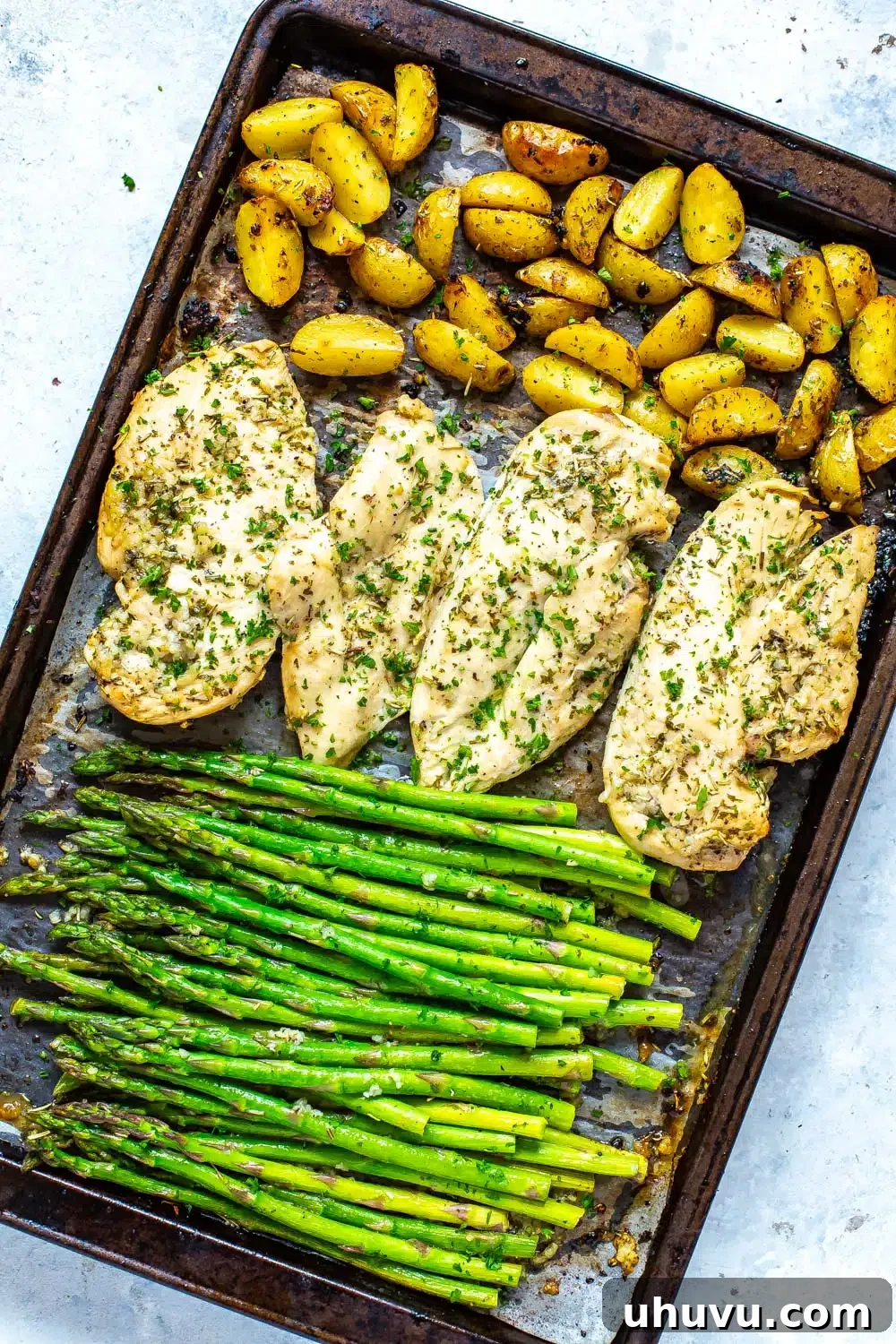 Baked Chicken and Asparagus on a baking sheet, ready for easy meal prep