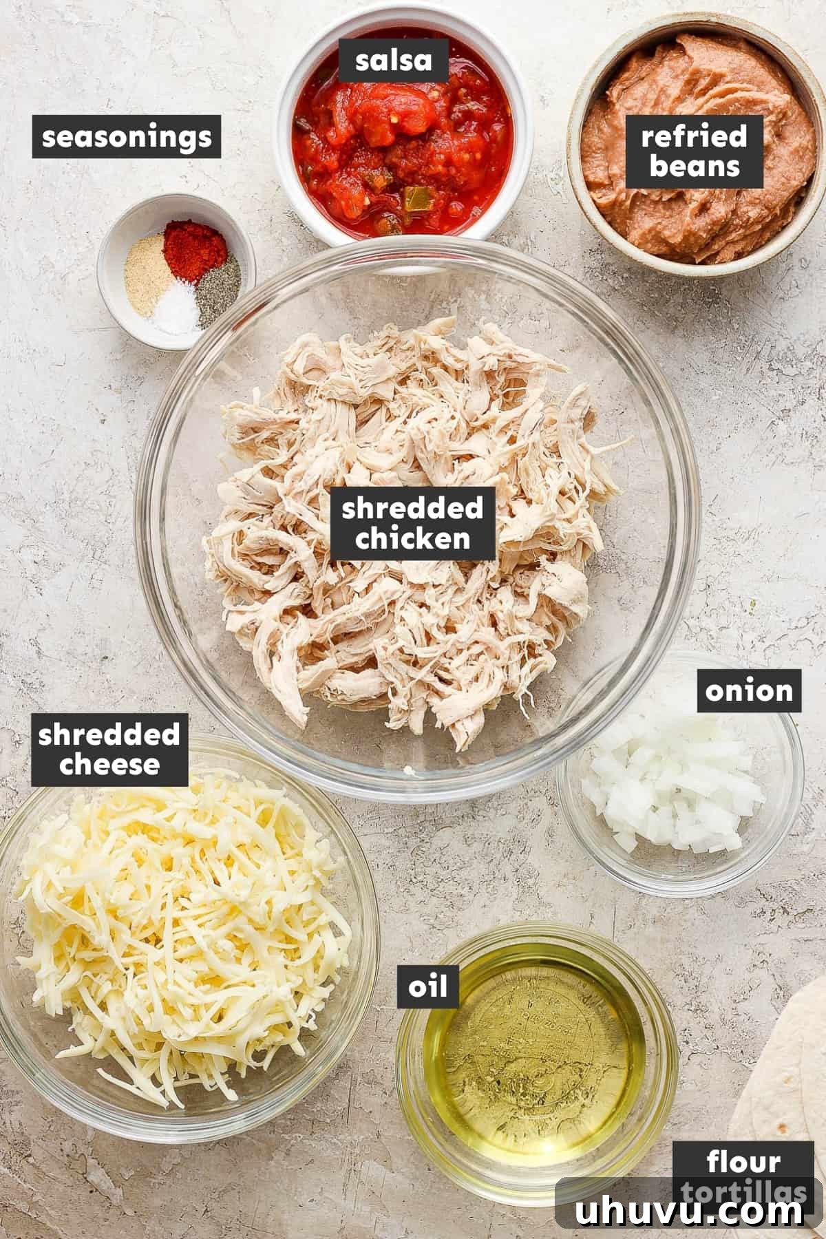 Golden Fried Delights 3 A vibrant display of fresh ingredients for chimichangas, including shredded chicken, canned refried beans, shredded cheese, salsa, and flour tortillas, neatly arranged on a rustic wooden table.