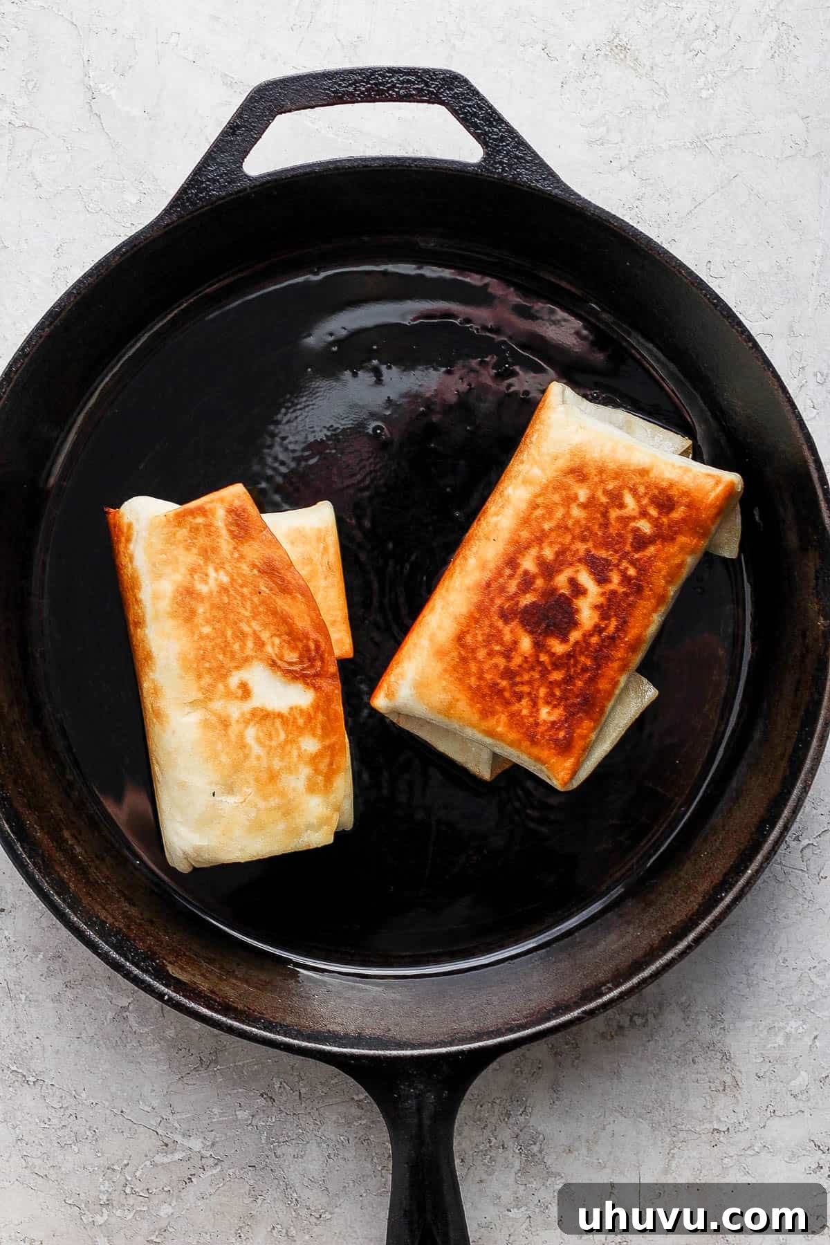 Golden Fried Delights 7 Two chimichangas sizzling in a skillet, pan-frying to a beautiful golden brown on top, promising a perfectly crispy exterior.
