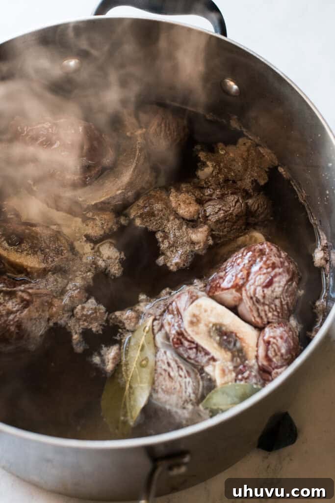 Heartwarming Beef and Vegetable Soup 5 Beef shanks, garlic, bay leaves, and salt simmering in a large pot of water to create the broth.