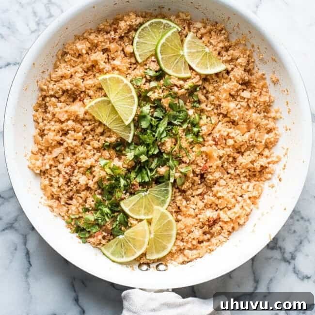 Fiesta Cauliflower Rice 6 Mexican cauliflower rice in skillet garnished with cilantro and lime.
