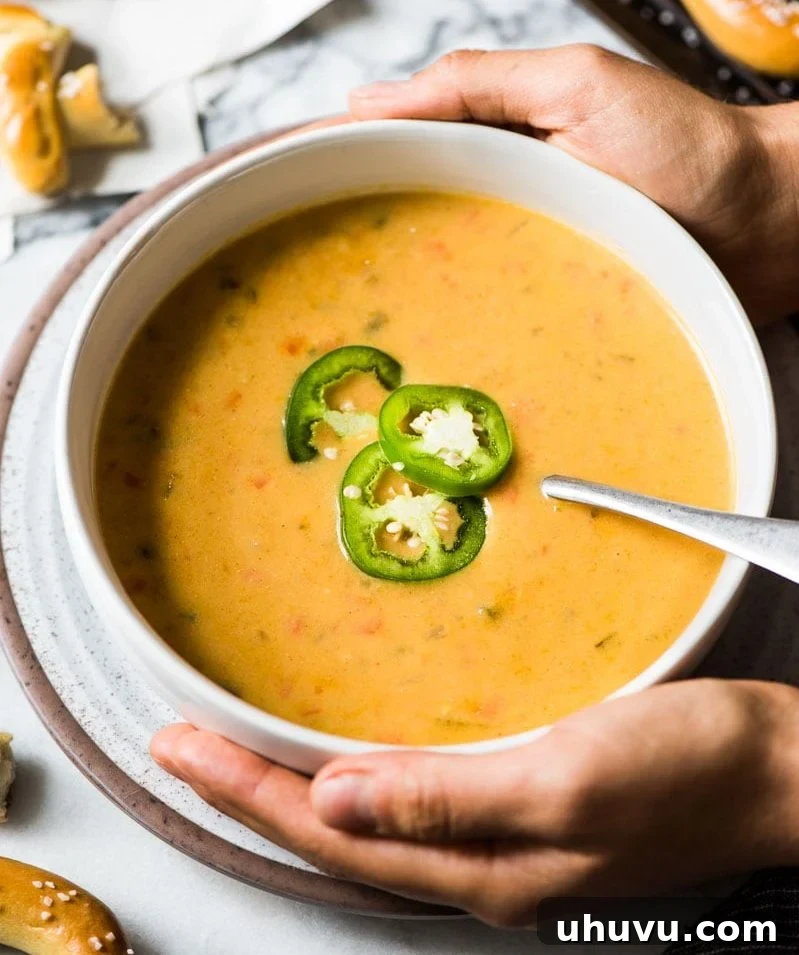 Golden Ale and Sharp Cheddar Bisque 8 Two hands gently holding a white bowl filled with warm beer cheese soup.
