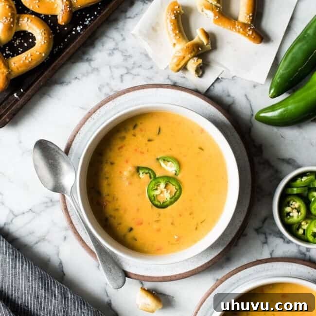 Beer cheese soup in a bowl with a side of soft pretzels