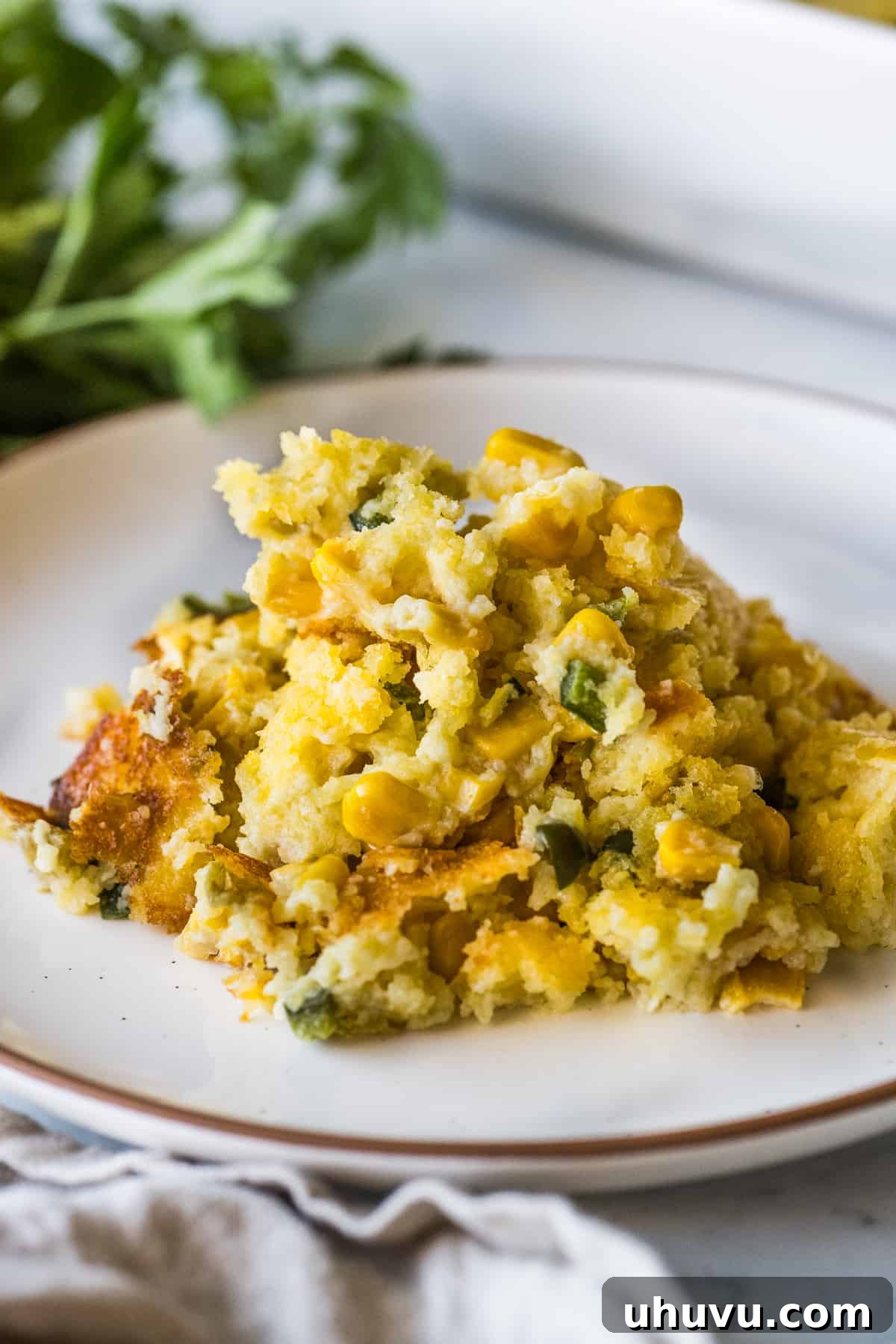 Zesty Green Chili Corn Bake 2 Green Chili Corn Casserole on a plate, garnished with fresh cilantro, ready to be enjoyed.