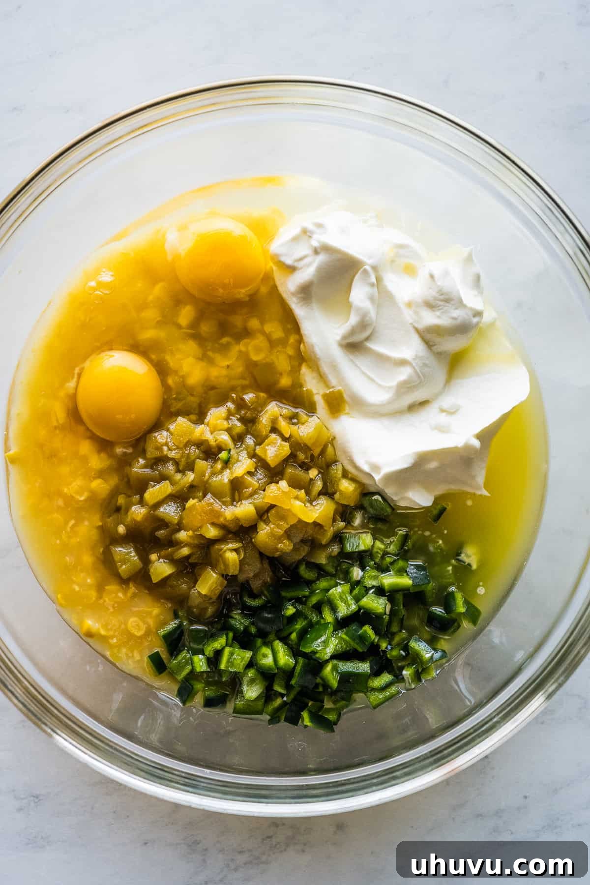 Zesty Green Chili Corn Bake 4 Eggs, sweet corn, creamed corn, diced green chiles, and sour cream are whisked together in a large mixing bowl, forming the creamy base of the casserole.
