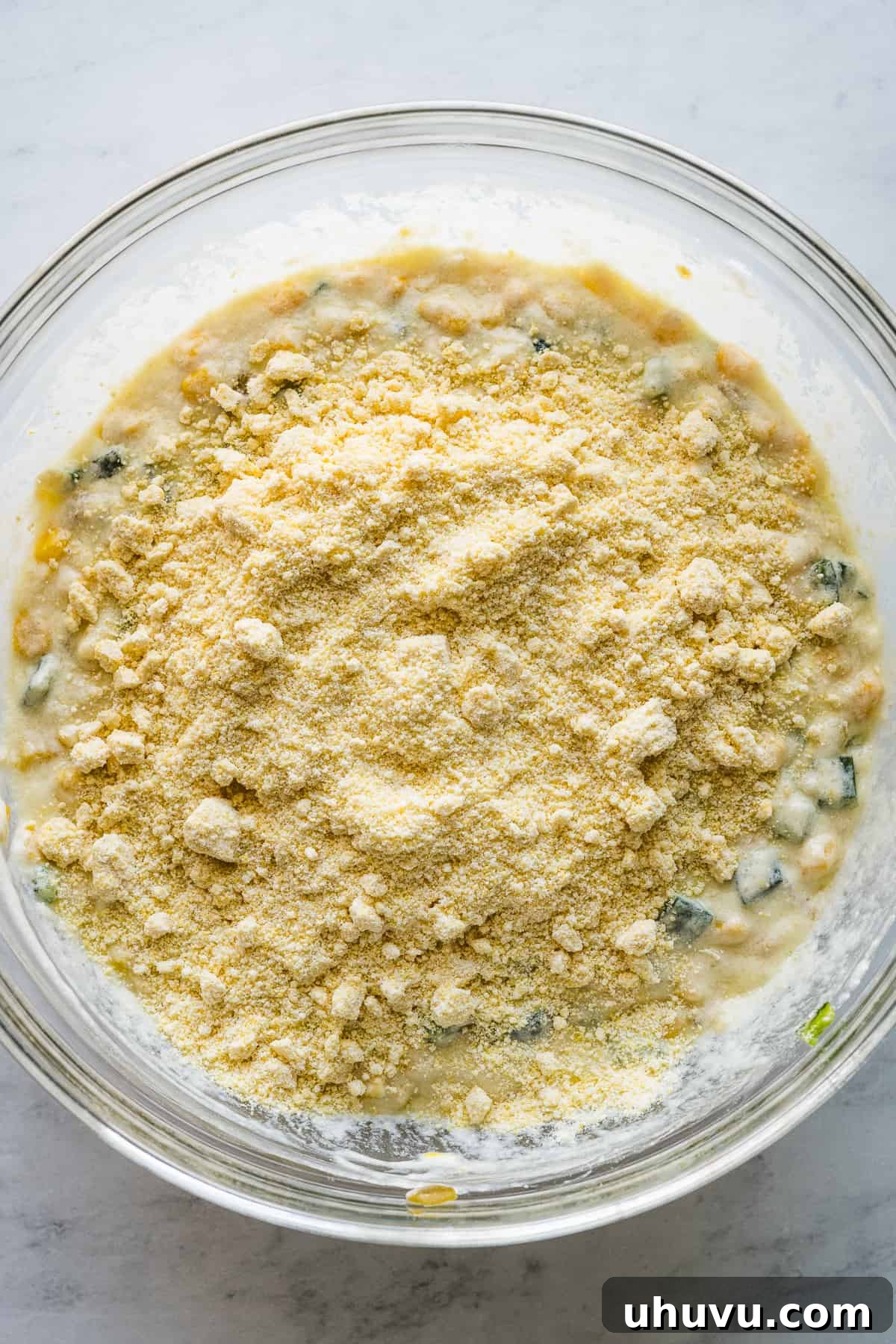 Zesty Green Chili Corn Bake 5 Jiffy corn muffin mix and shredded cheese are added to the bowl of wet ingredients, ready to be whisked into the green chili corn casserole batter.
